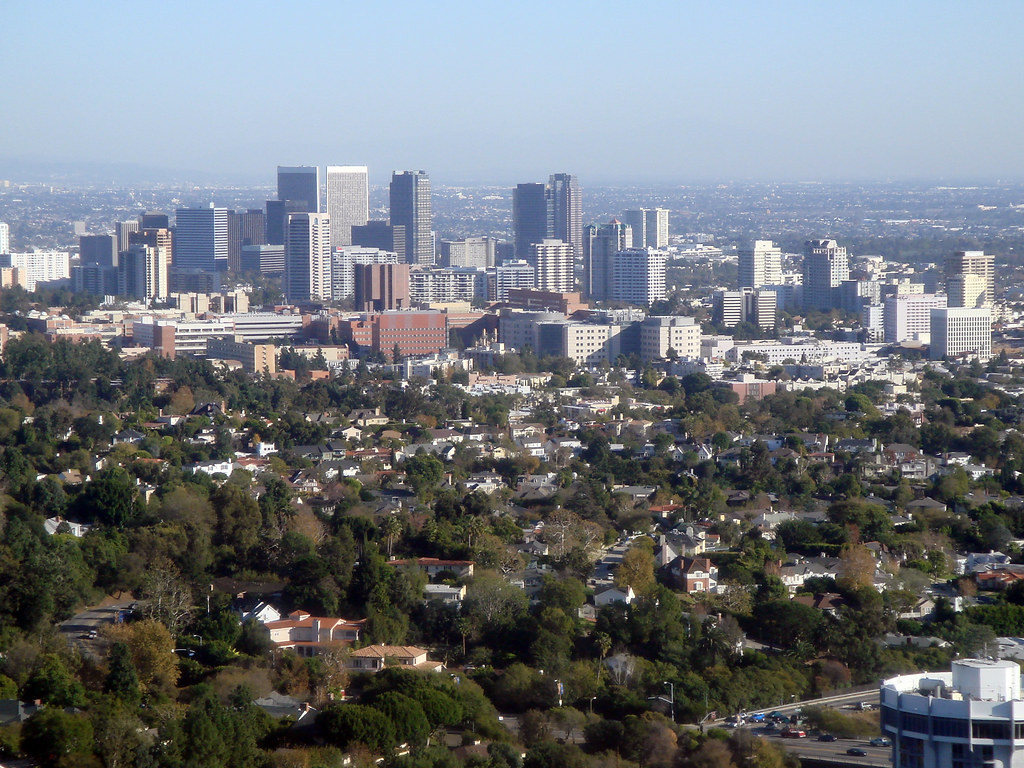 A city skyline with residential areas and greenery in the foreground.