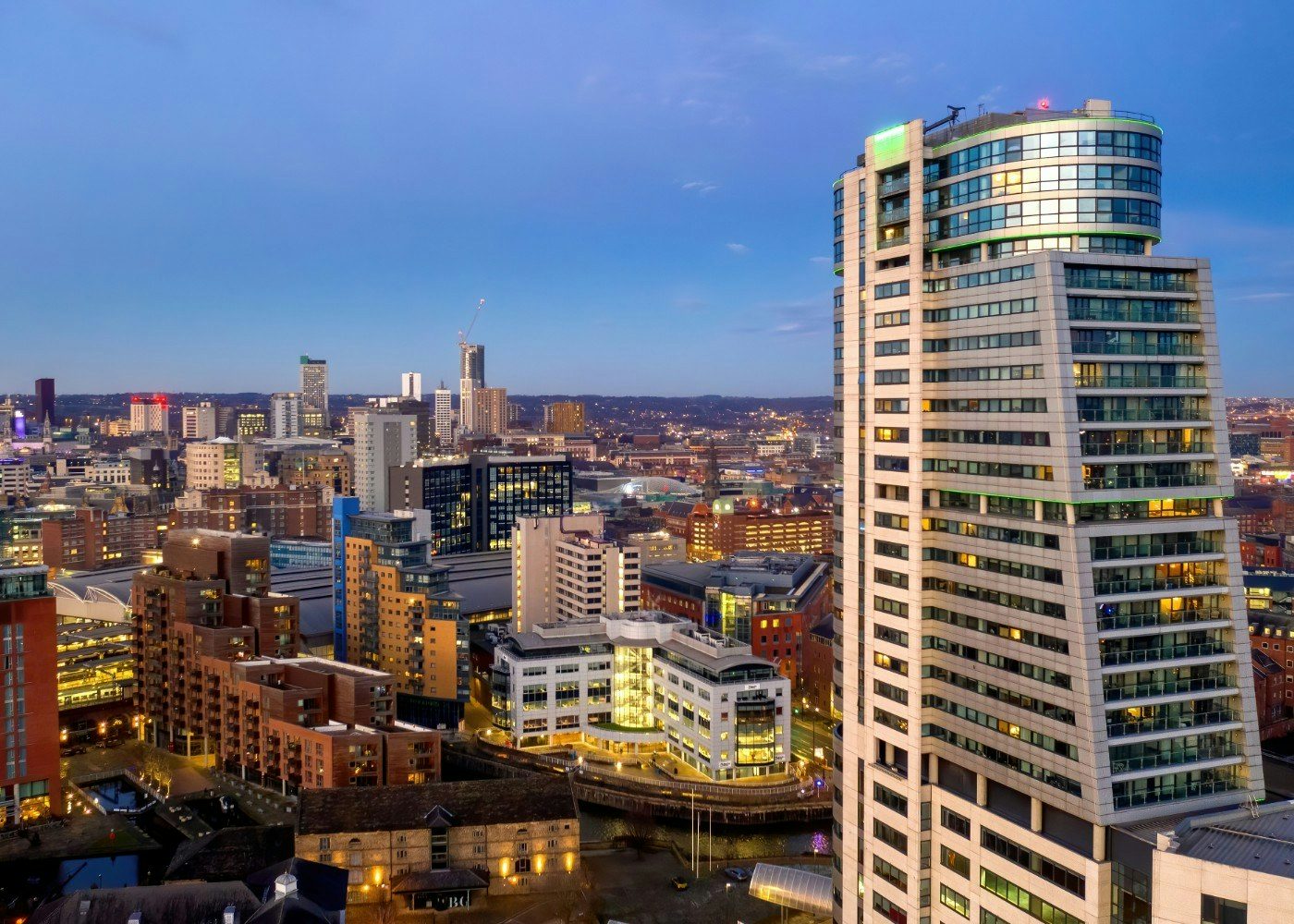 City skyline with modern high-rise and older buildings at dusk.