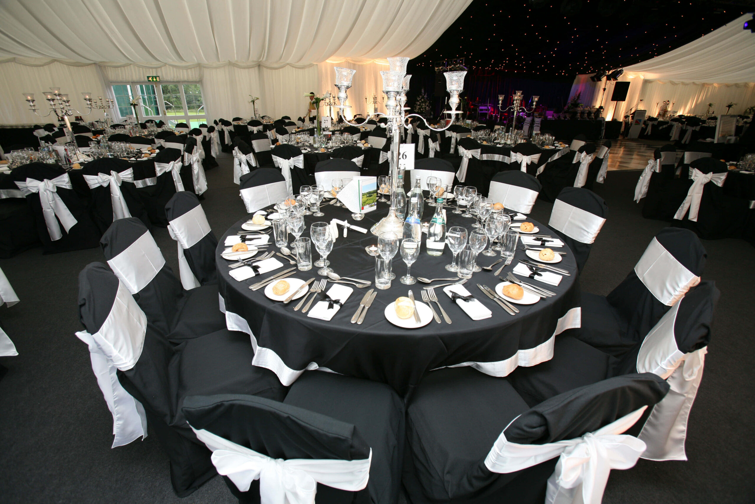Elegant black and white banquet setup with round tables and candle centerpieces.