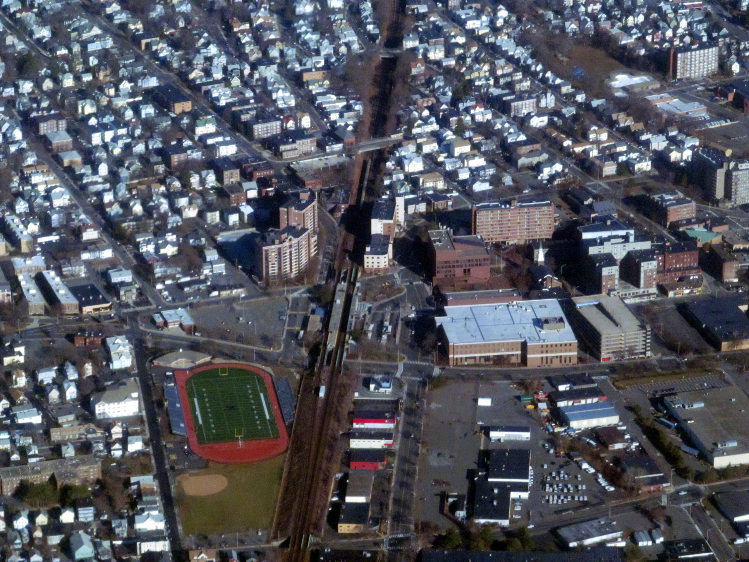 Aerial view of a city with a sports field and dense buildings.