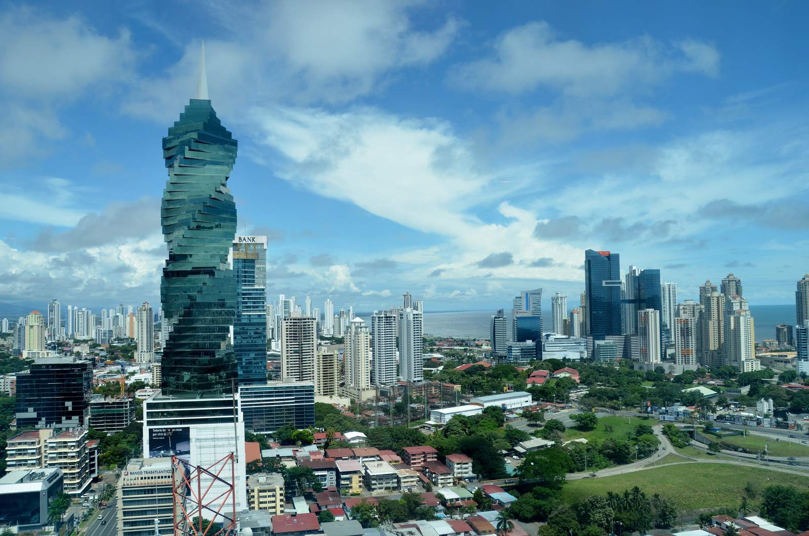 Cityscape with a unique twisted skyscraper under a partly cloudy sky.
