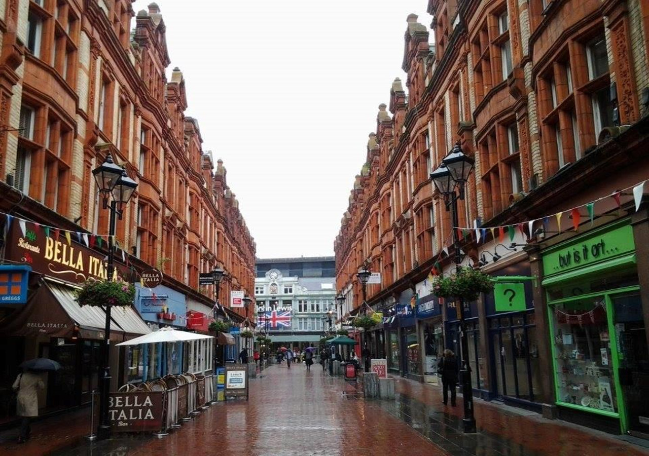 A vibrant street with red brick buildings and shops on both sides.