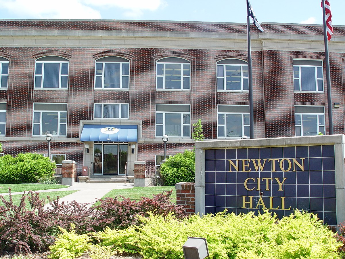 Newton City Hall building with a flagpole and garden in front.