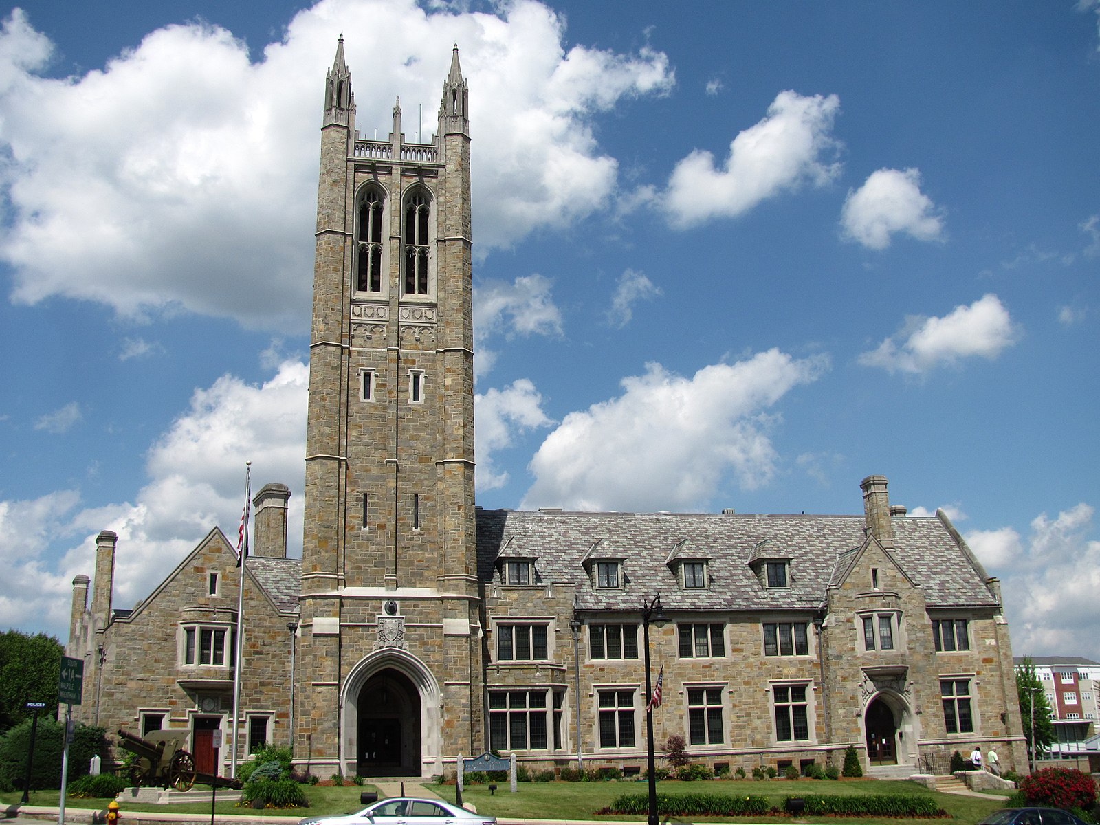 Historic stone building with a tall clock tower under a blue sky.