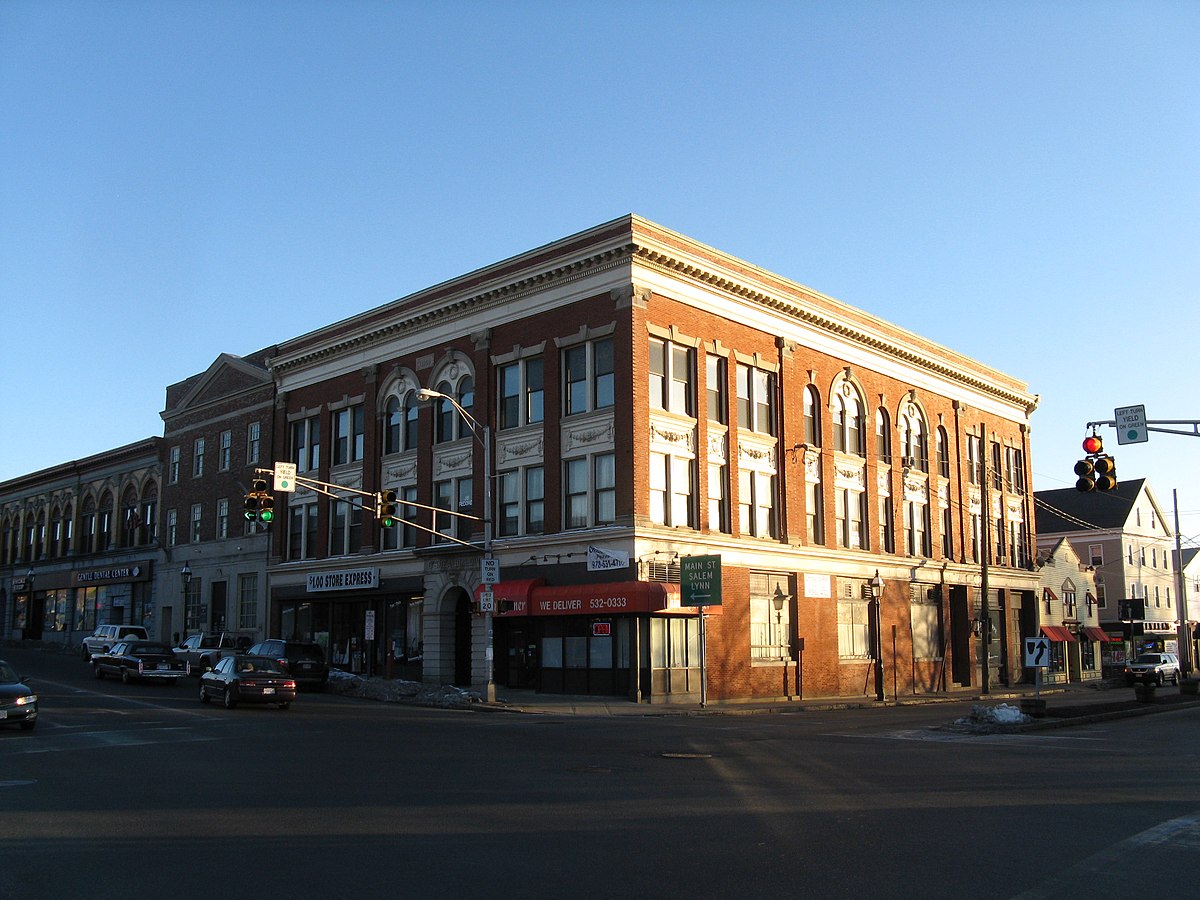Historic brick building on a sunny street corner under a clear blue sky.
