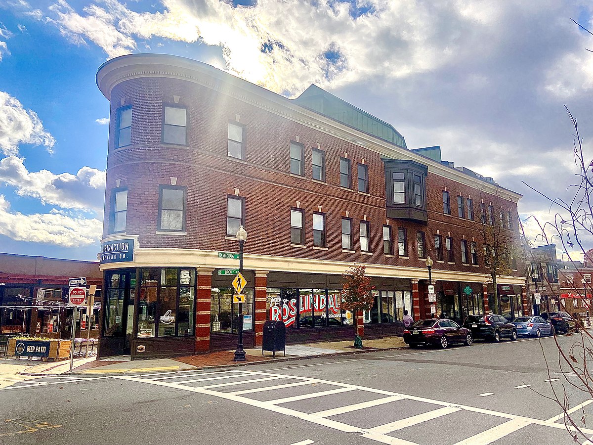 Historic brick building on a sunny street corner with shops below.