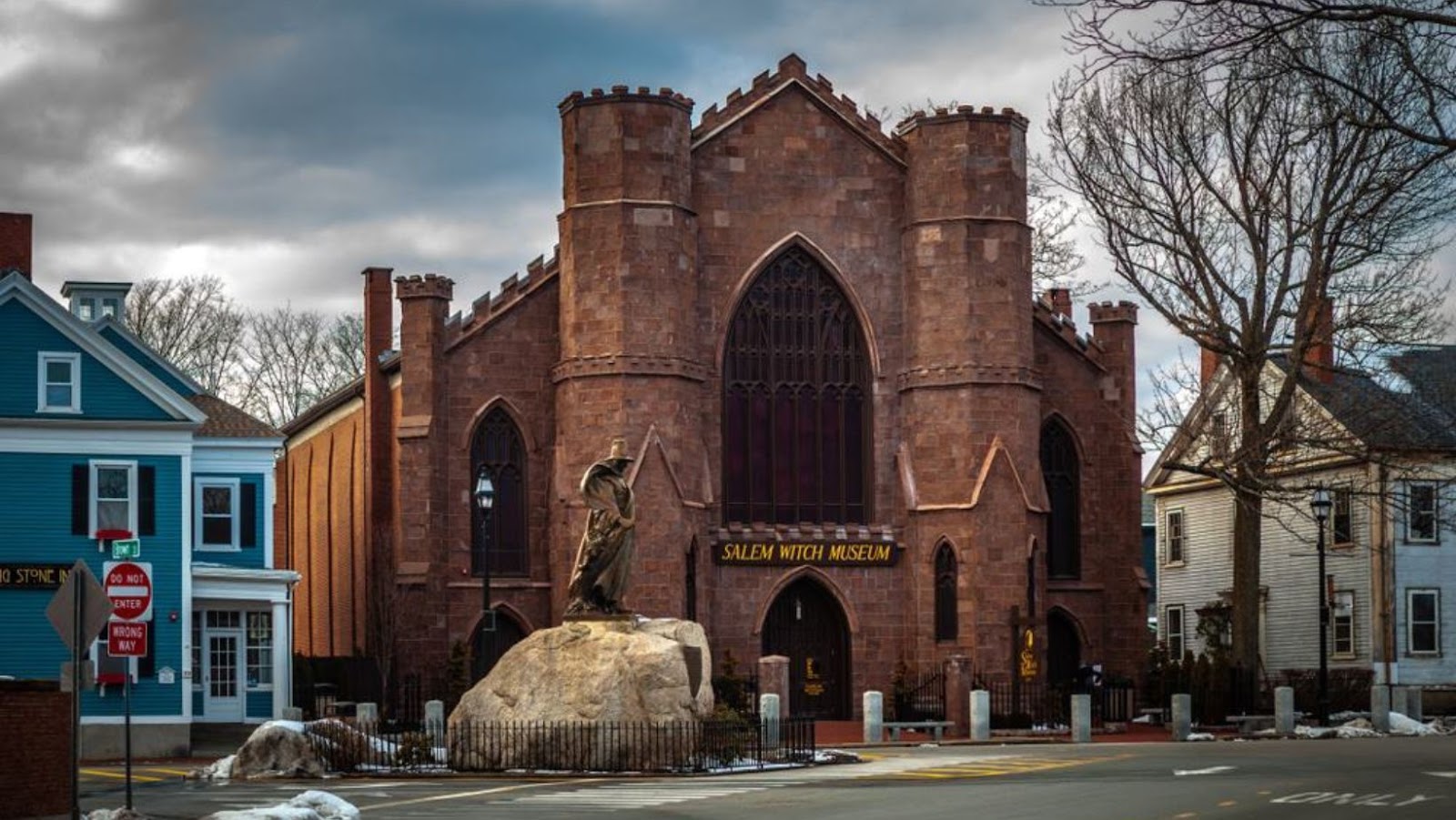 Gothic-style brick building with arched entrance and large rock sculpture outside.