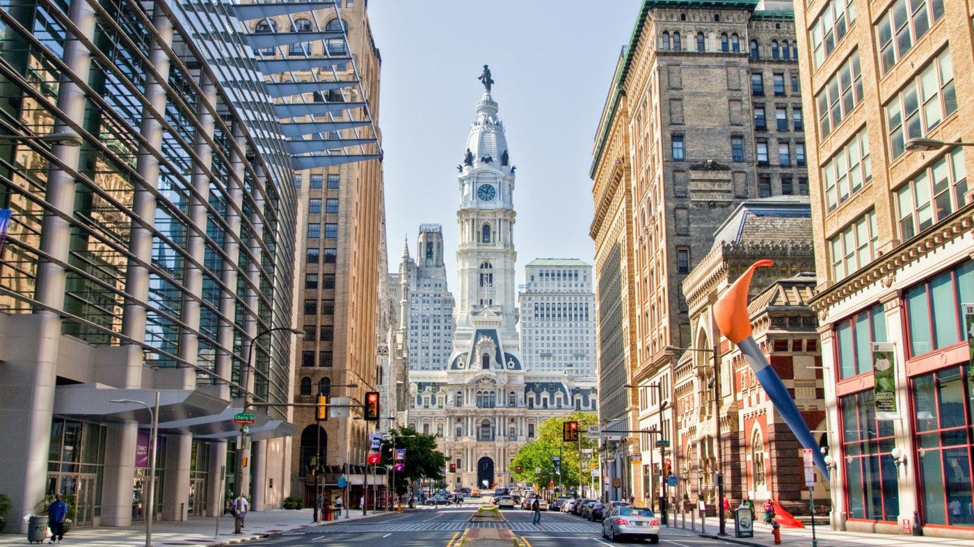 View of Philadelphia City Hall framed by tall buildings on a clear day.