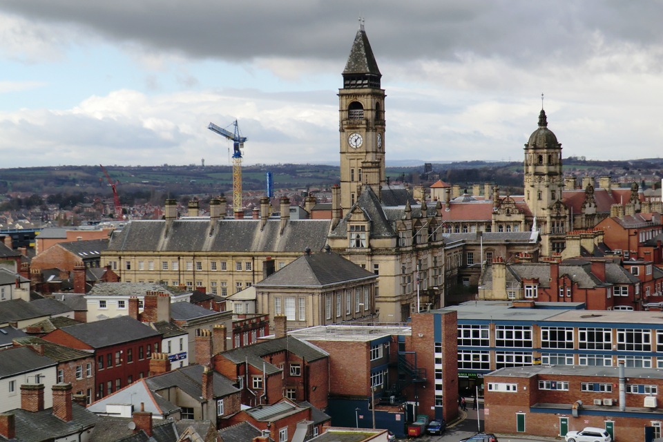 Cityscape featuring historic clock tower and modern buildings under cloudy sky.