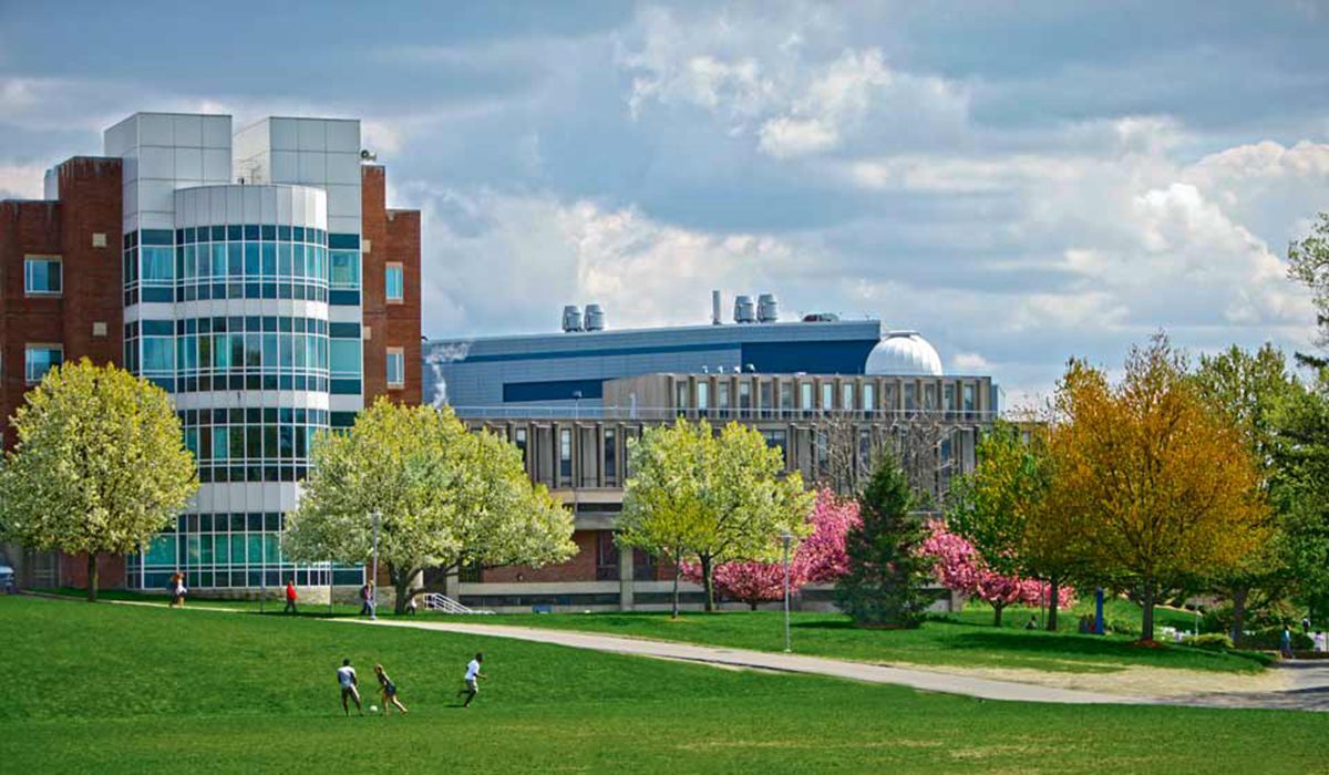 A green campus with students walking and colorful trees in spring.