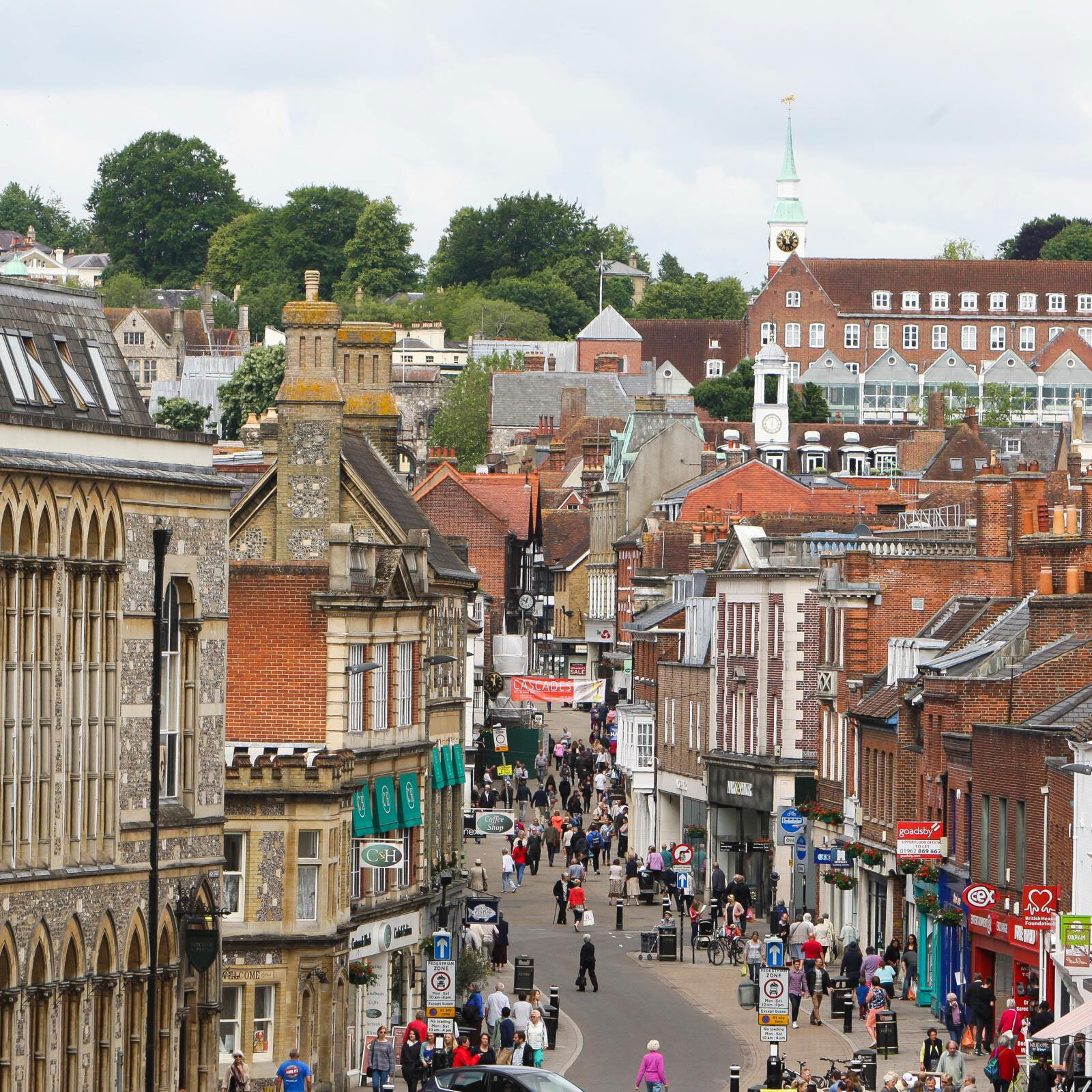 Bustling street scene in a historic town with shops and pedestrians.