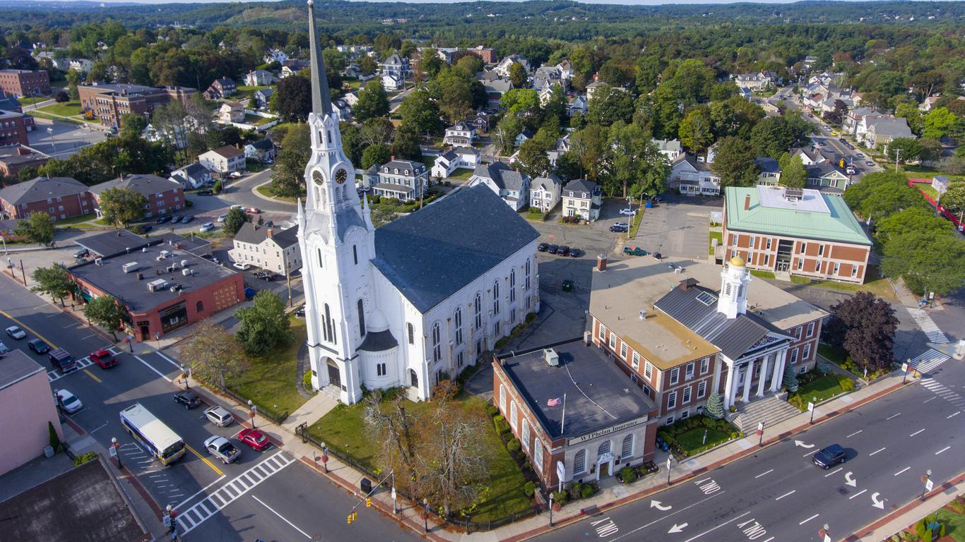 A white church with a tall steeple in a residential neighborhood.