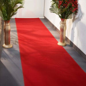 Red carpet runner flanked by floral arrangements in vases.