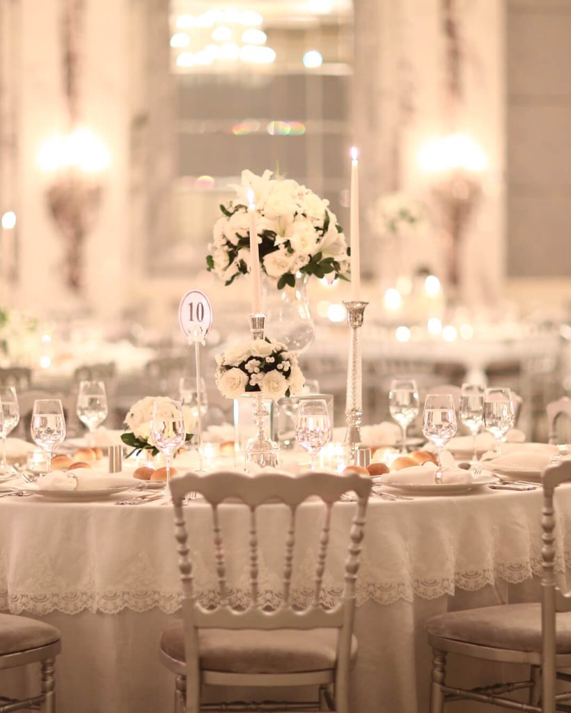 Elegant wedding reception table with floral centerpiece and soft lighting.